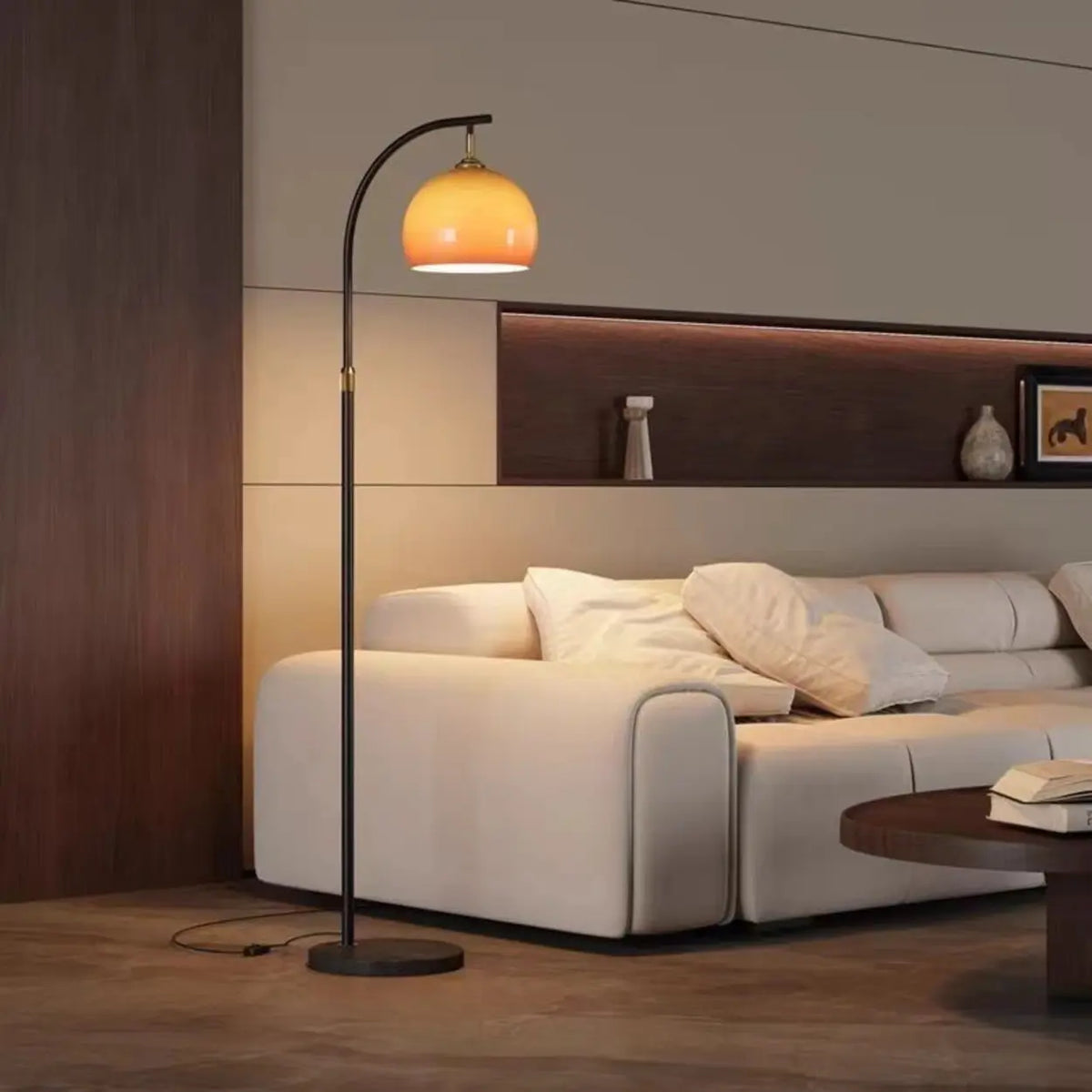 Brass-accent caramel glass arc floor lamp providing downward light in a modern living room