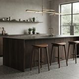 Row of coffee-brown faux leather counter stools with curved seats, wood frames and black footrests at a modern kitchen island