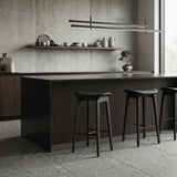 Row of black faux leather counter stools with curved seats, dark wood frames and black footrests at a contemporary kitchen island