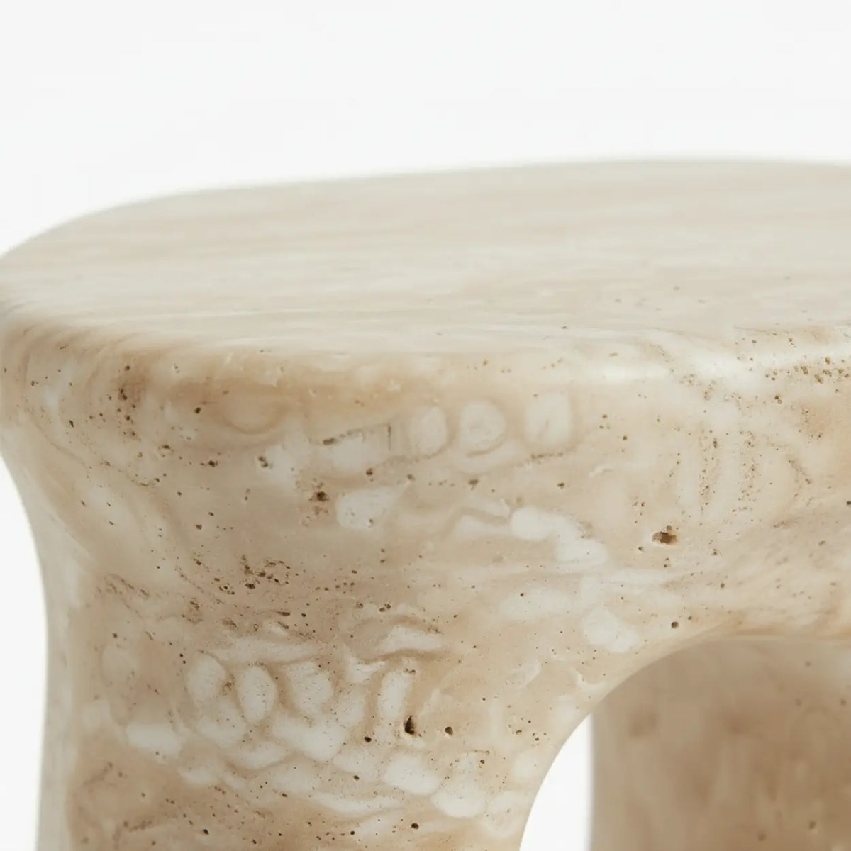 Close-up of the faux travertine stone oval side table showing its rounded edge and mottled stone texture