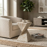 Travertine faux stone side table with a twisted geometric pedestal beside a cream boucle sofa, styled with a cup in a modern living room