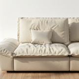 Beige suede modular sofa close-up showing textured seat cushions, padded backrests and accent pillow