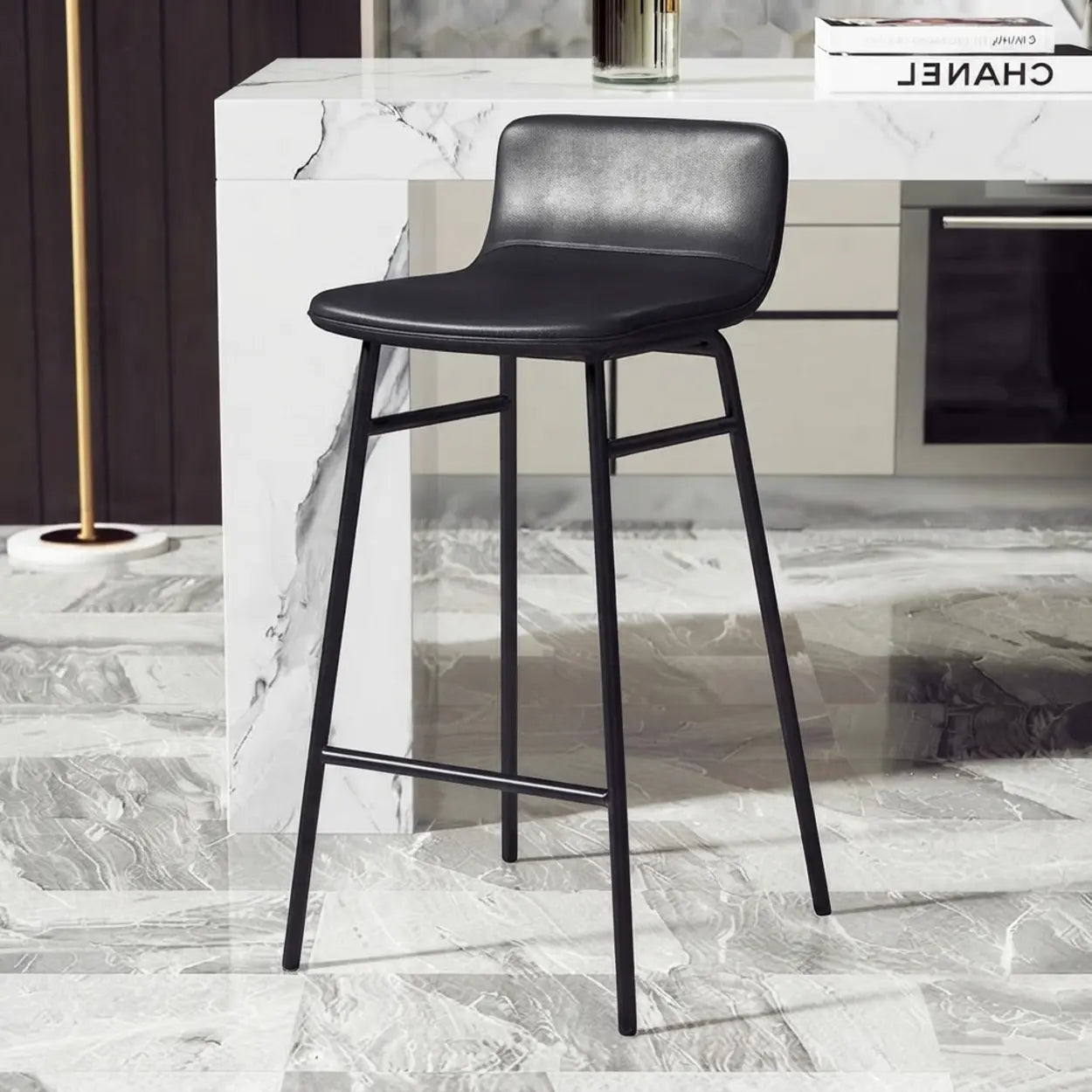 Black faux leather bar stool with a seamless curved seat-and-back profile, slim black metal legs and integrated support rails in a marble kitchen