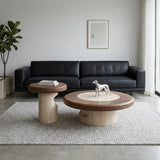 Walnut round coffee table set with large and small wood-veneer tables, cream stone inlay and curved stone bases in front of a black sofa